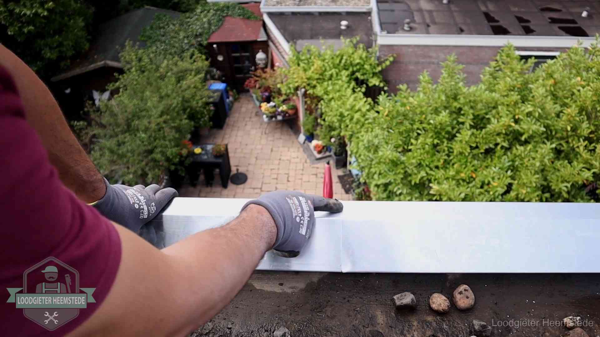 Vakman plaatst een daktrim op de dakrand van een woning in Heemstede