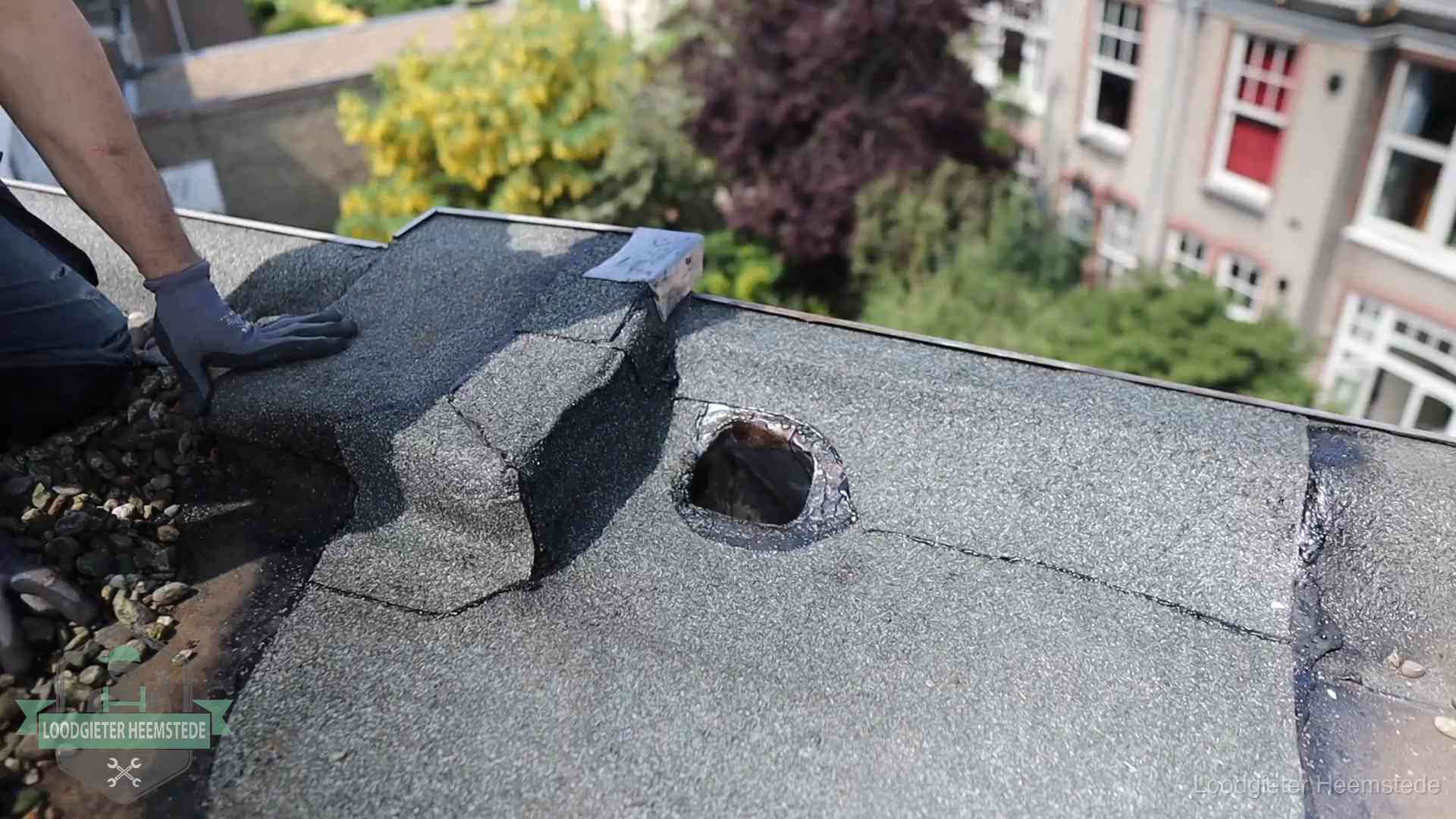 Loodgieter inspecteert een beschadigd bitumen plat dak tijdens een daklekkage-inspectie in Heemstede