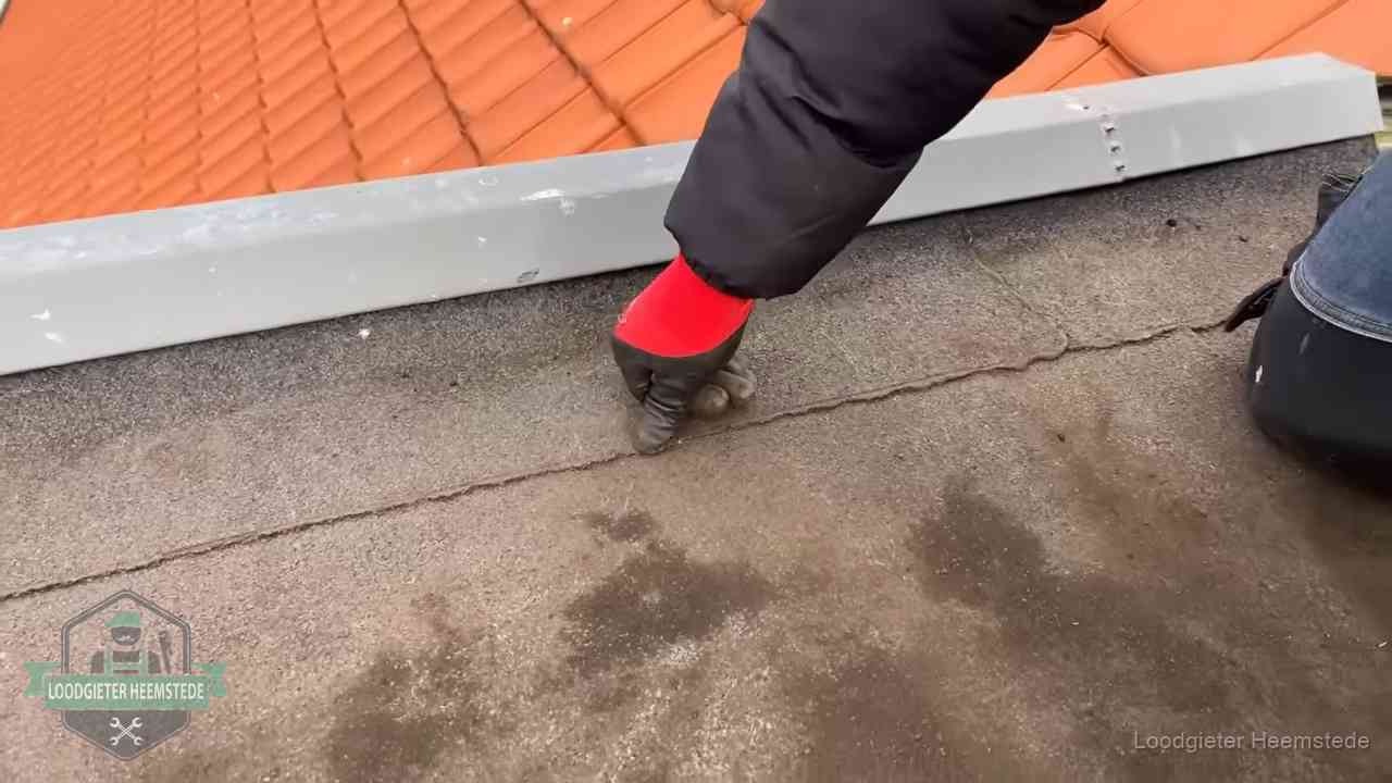 Vakman wijst een naad met vochtplekken aan op een bitumen plat dak in Heemstede