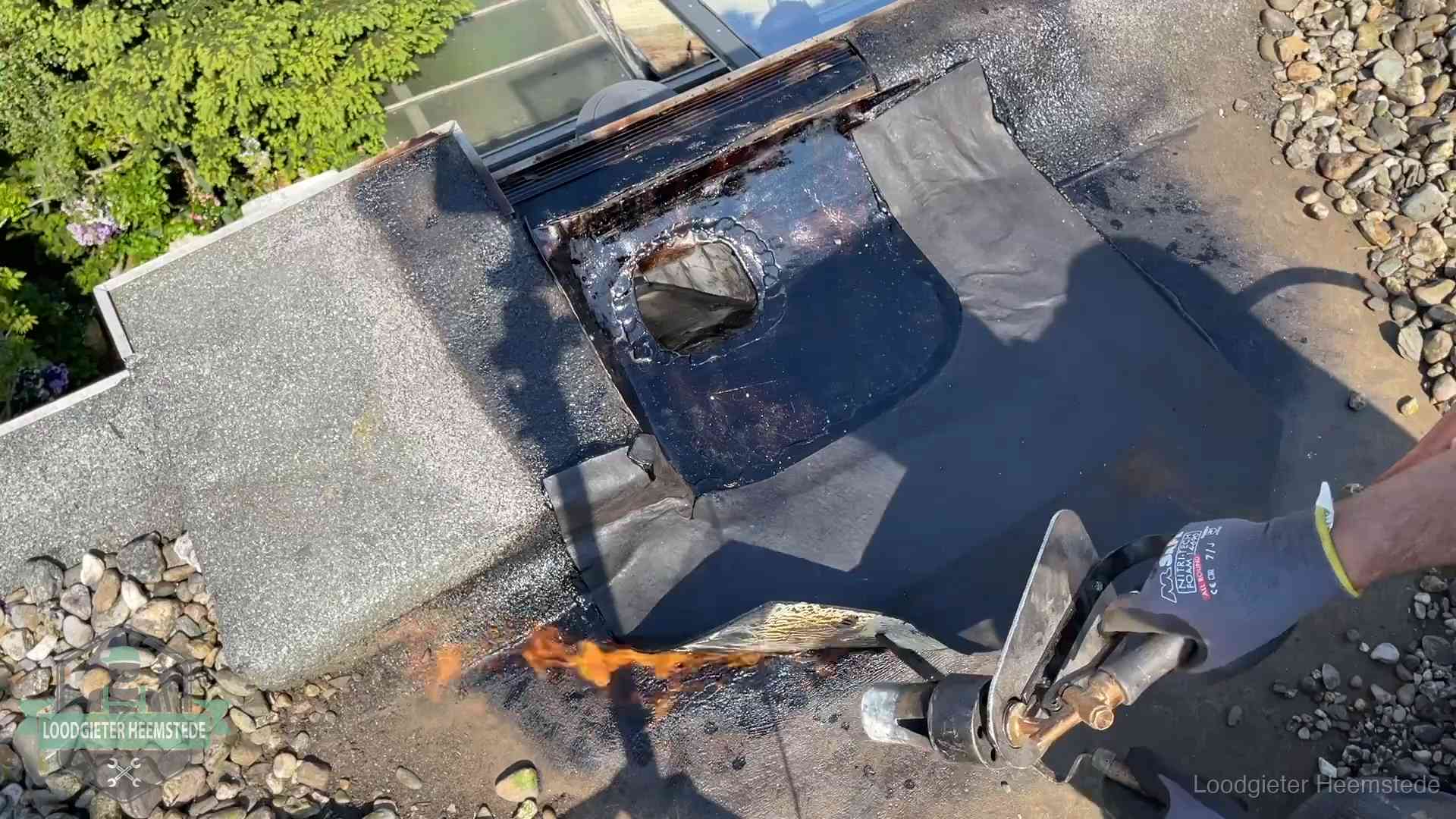 Dakdekker brandt bitumen rond een doorvoer tijdens een daklekkage-reparatie in Heemstede