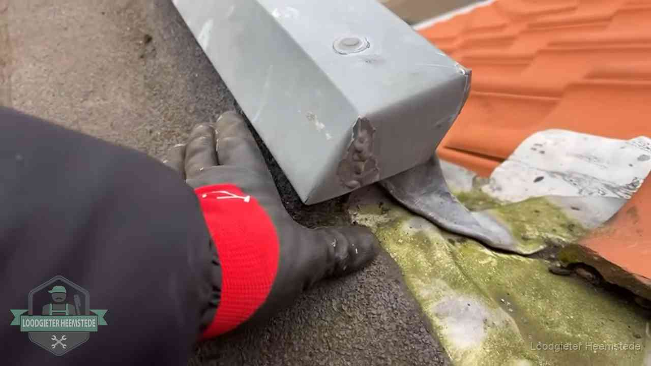 Controle van een zinken hemelwaterafvoer met loodslab bij dakpannen in Heemstede