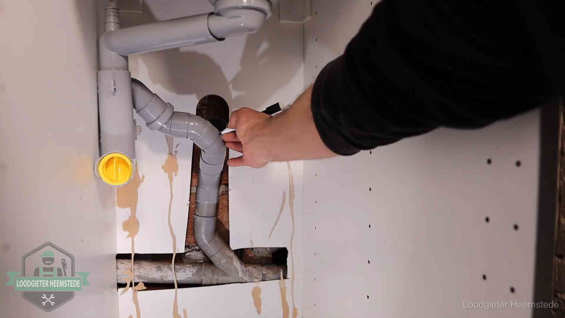 Loodgieter markeert een pvc-afvoerbuis onder een gootsteen in Heemstede