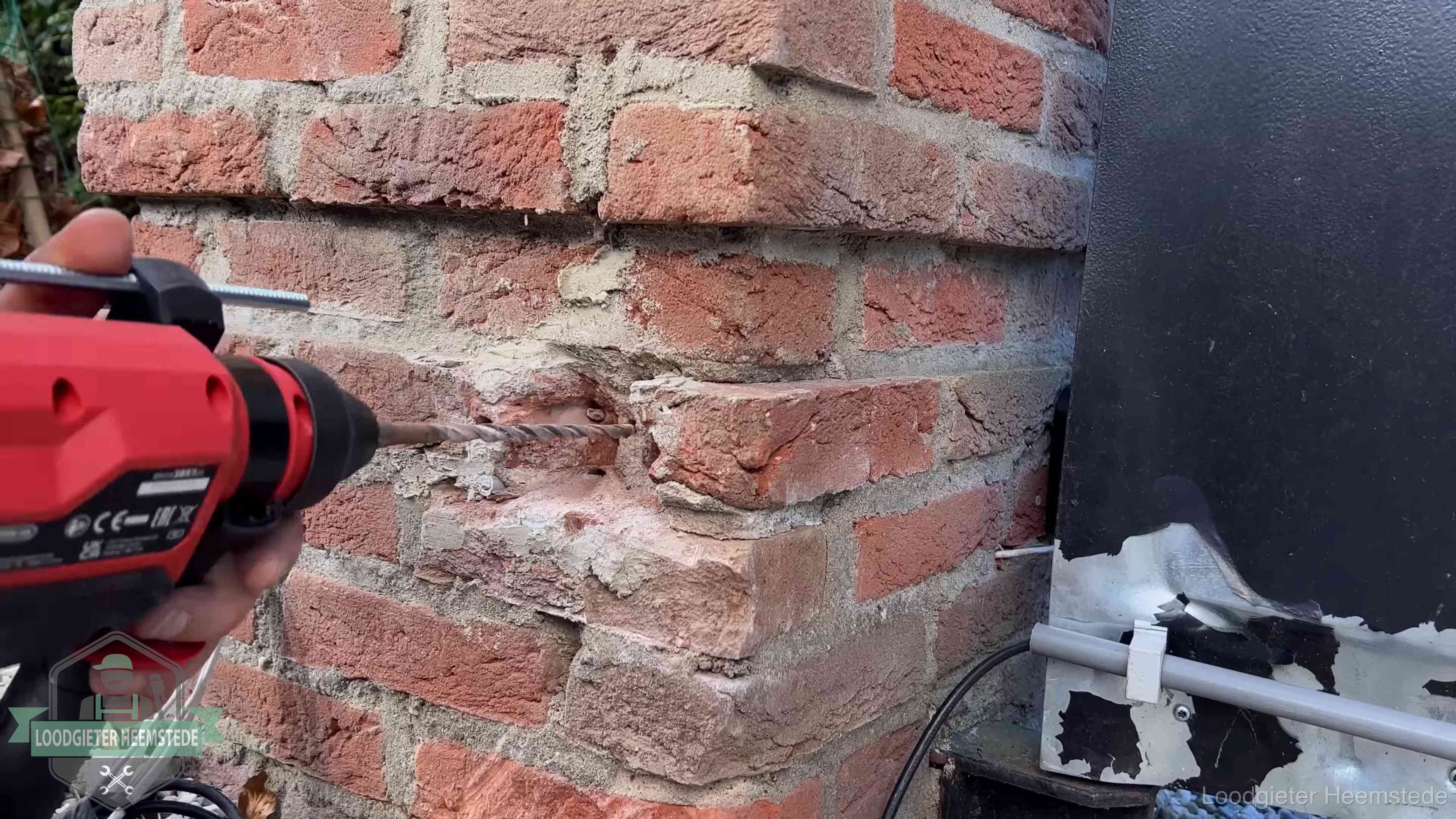 Vakman boort in de buitenmuur van een woning in de regio Heemstede