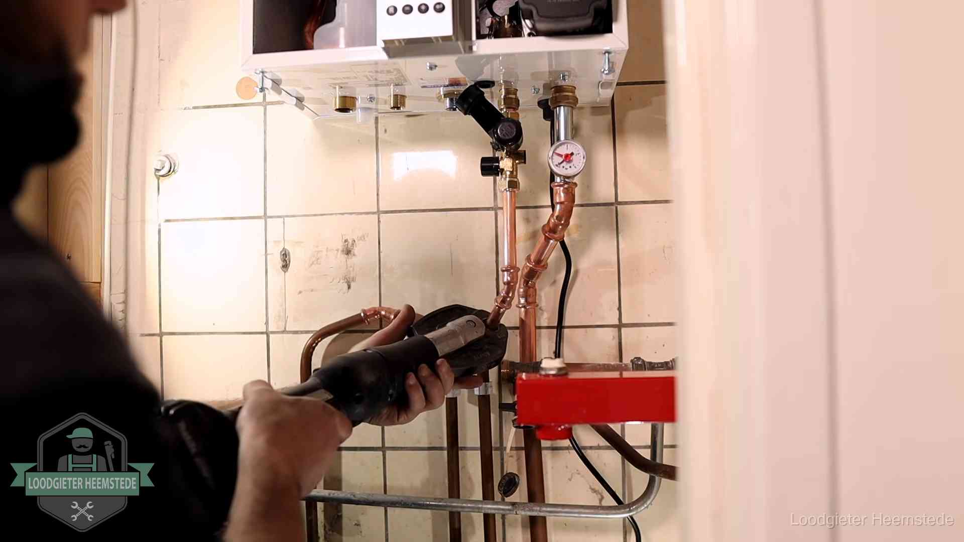 Monteur werkt aan de leidingen onder een cv-ketel in Heemstede