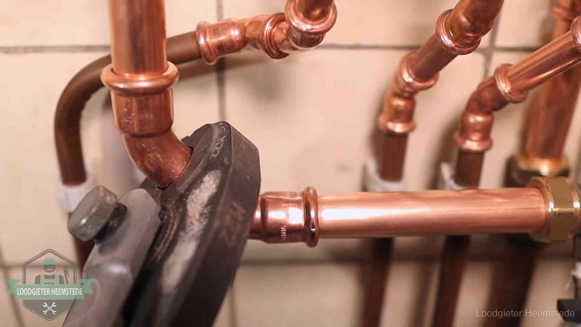Persmachine perst een koperen fitting op nieuw leidingwerk in Heemstede