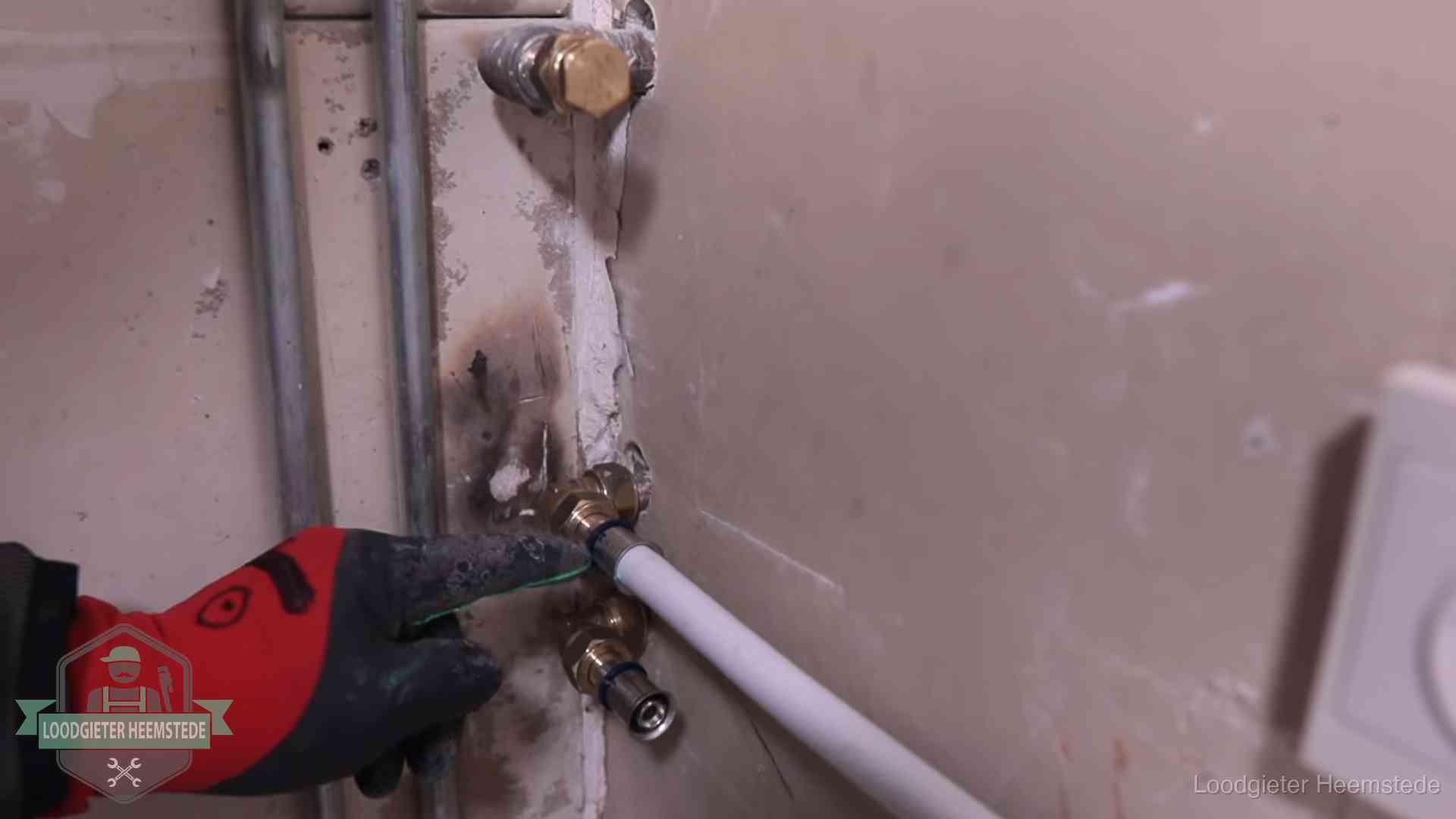 Loodgieter wijst de persfitting op nieuwe muuraansluitingen aan in een woning in Heemstede