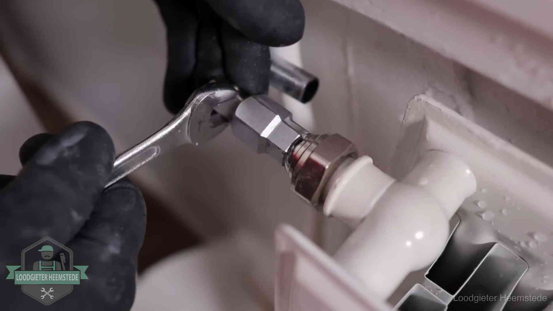 Steeksleutel draait een wartelkoppeling op een radiatorkraan aan in Heemstede