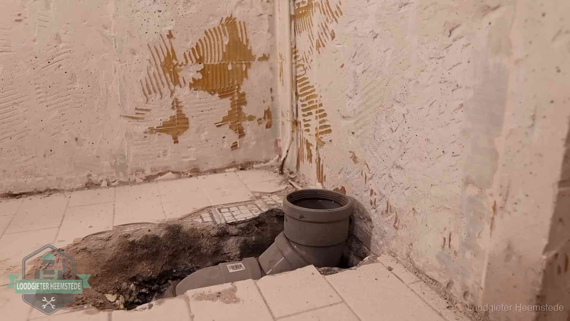 Verzakt riool herstellen in Heemstede Opengebroken vloer met een nieuwe pvc-rioolbocht in een gegraven sleuf in Heemstede