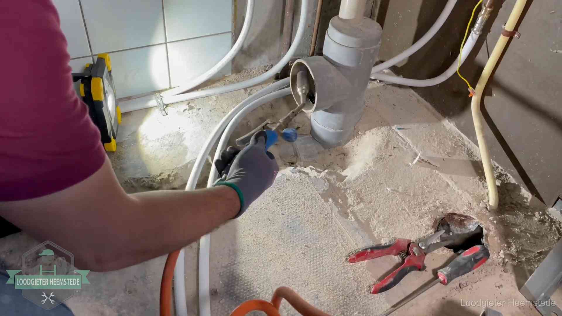 Loodgieter werkt aan leidingen bij een pvc-standleiding in een appartement in Heemstede
