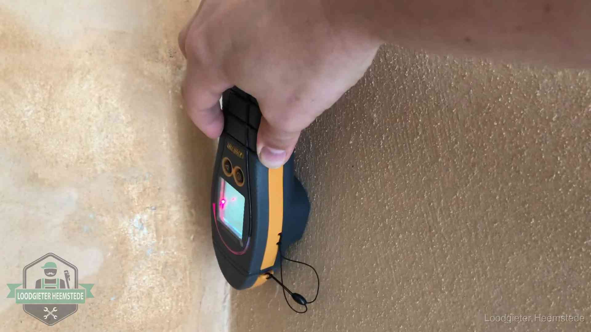 Vochtmeter tegen een muur met vochtplekken tijdens het opsporen van een daklekkage in Heemstede